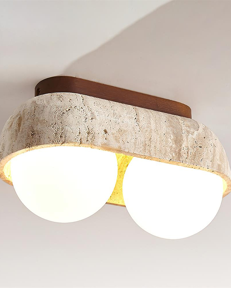 Close-up of the lit PIETRA No.03 travertine flush mount ceiling light, Two-Globe in Walnut, warm glow between the globes