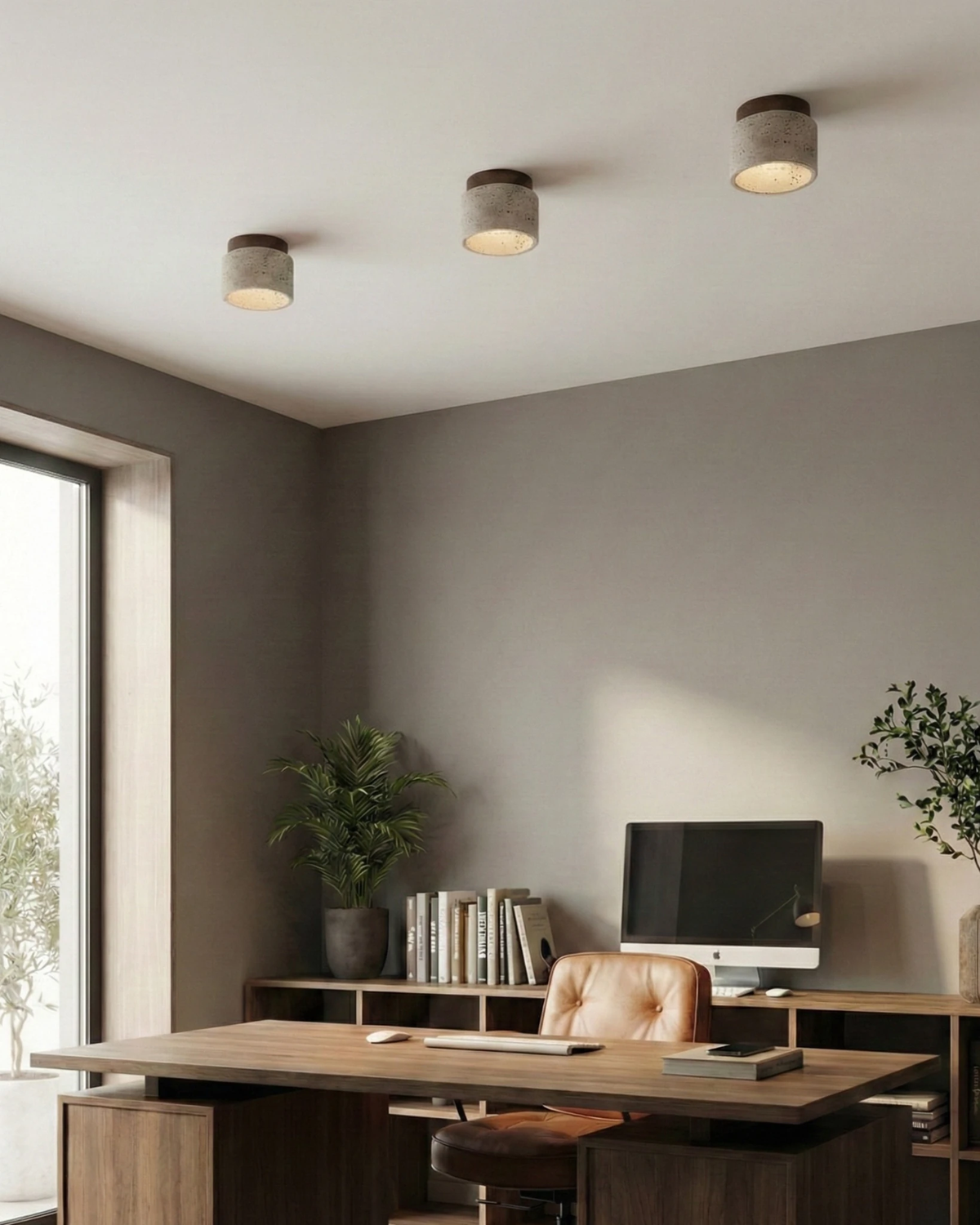 Three travertine flush mount ceiling lights VERTIN No.05 lit on a gray office ceiling above a walnut desk and leather chair