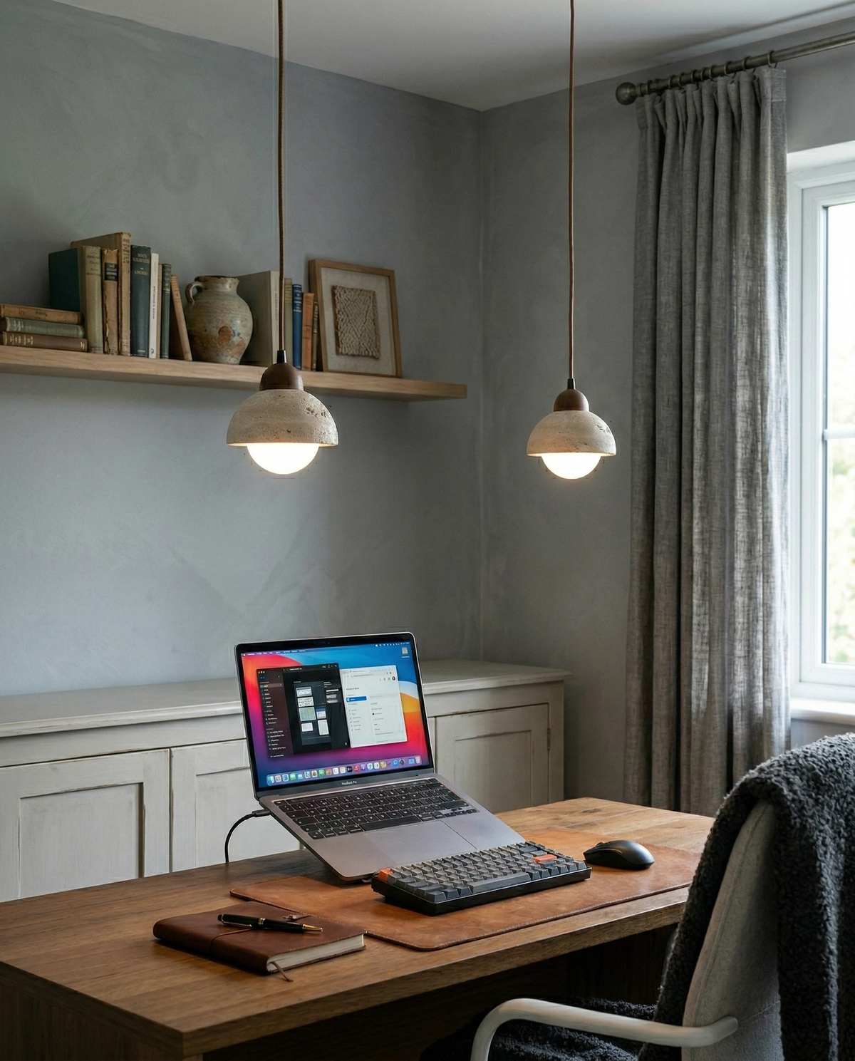 Two travertine pendant lights AVORIO No.04 lit above a wooden desk with a laptop and a floating shelf