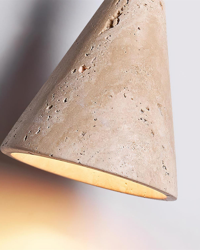 Close-up of the PIRA No.01 travertine pendant light cone, pitted stone with warm light from the opening