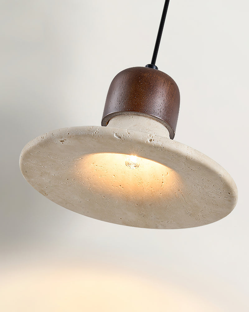 Close-up of the SOVA No.03 travertine pendant light, flared shade lit from within with a walnut cap, angled view