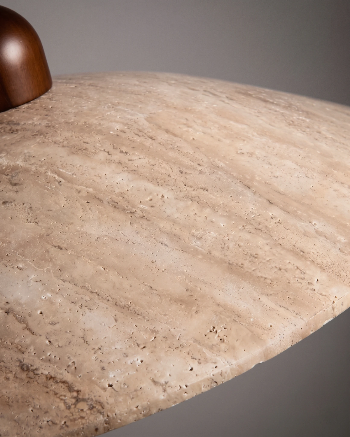 Close-up of the cream travertine saucer surface and walnut cap of the TONDO No.01 travertine pendant light