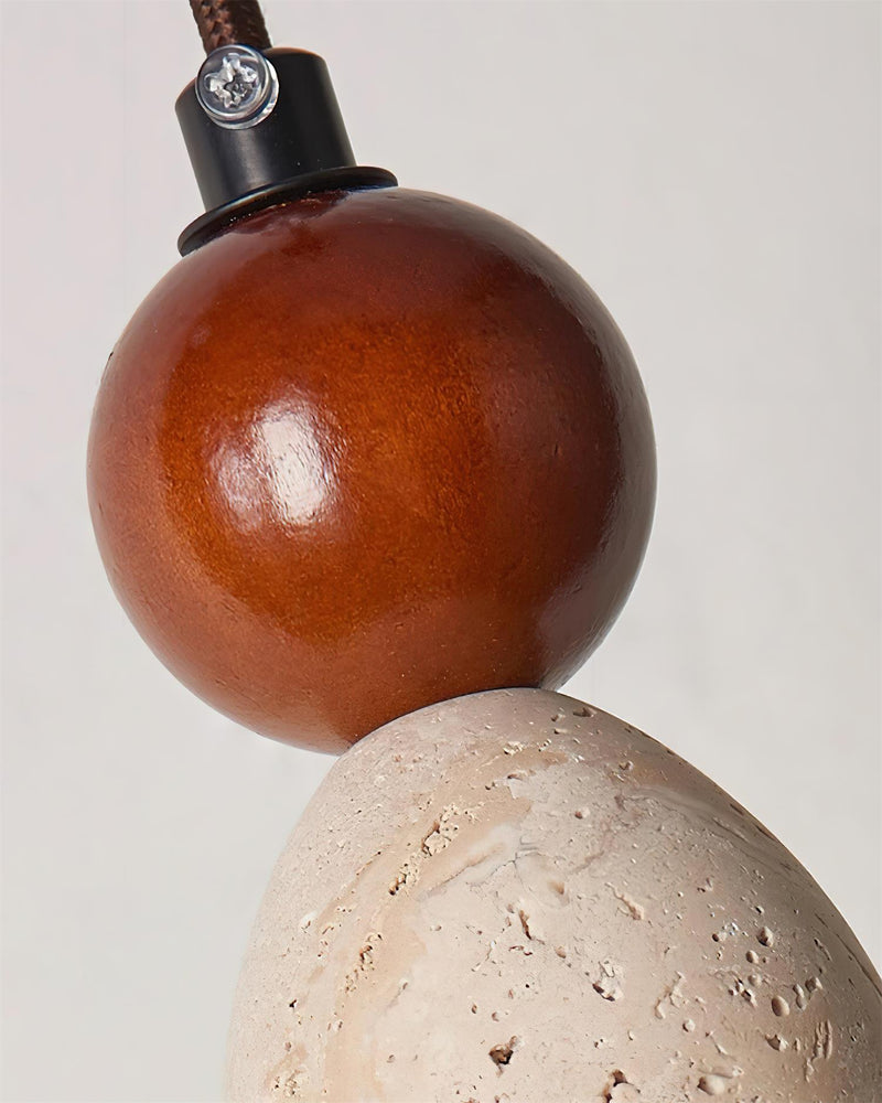 Close-up of the walnut sphere resting on the travertine ball of the travertine pendant light DOMUS No.04