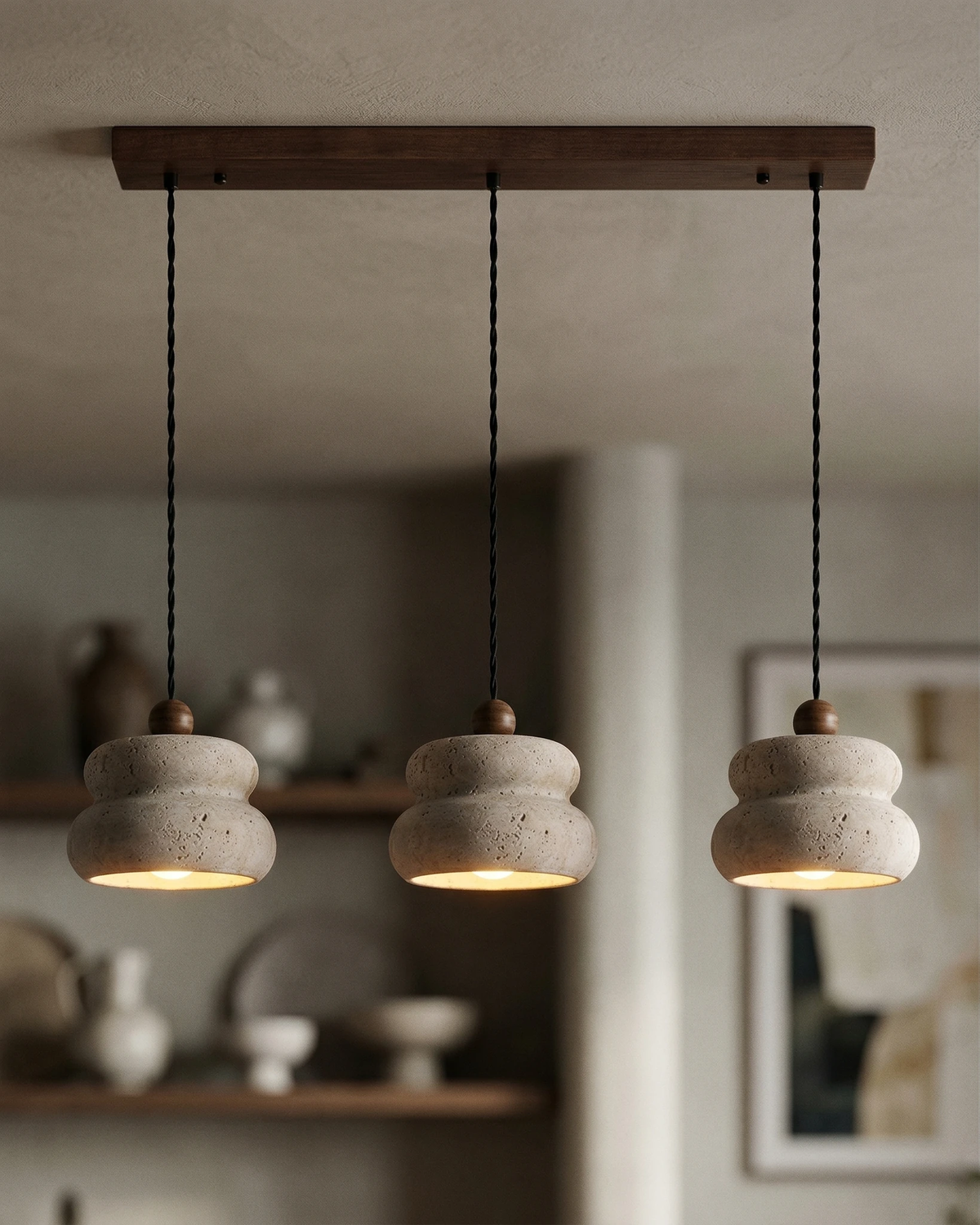Travertine pendant light SOVA No.05 triple cluster lit in front of open shelves of ceramics in a kitchen