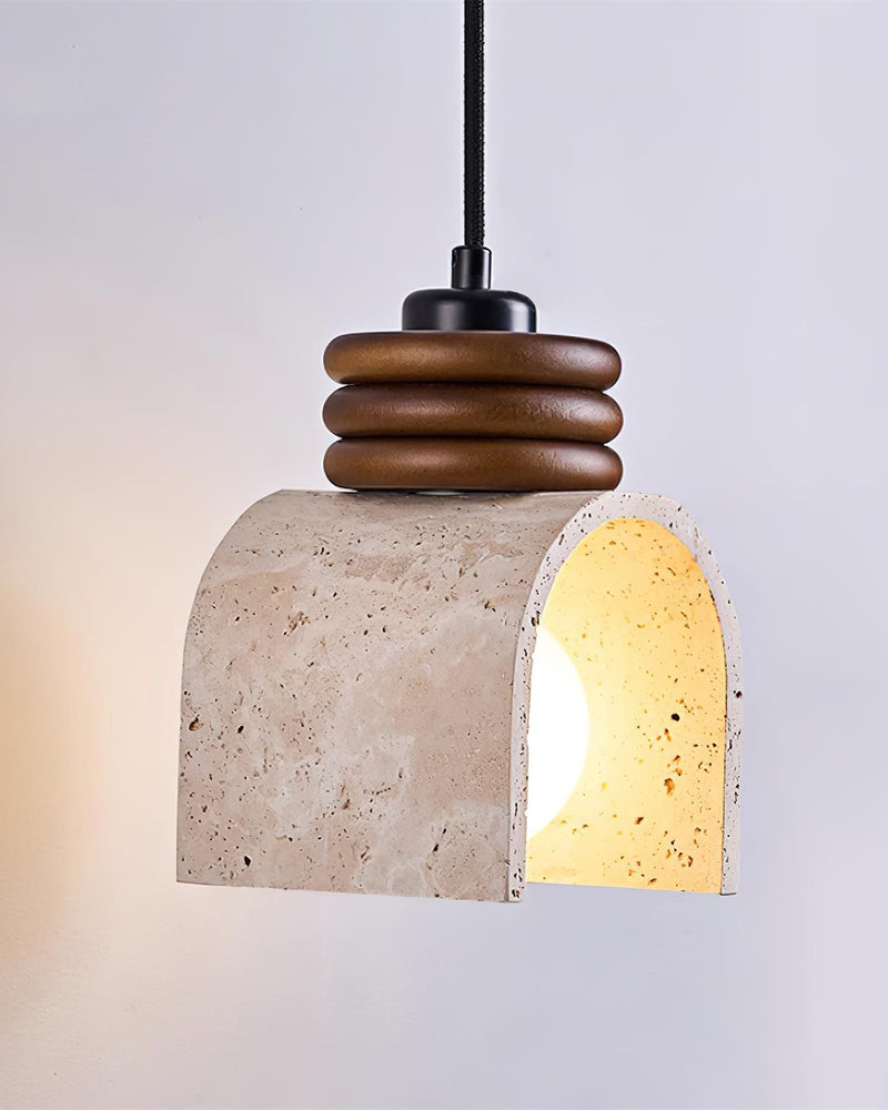 Travertine pendant light ARCA No.02 lit and turned to the side, warm light filling the curved travertine vault