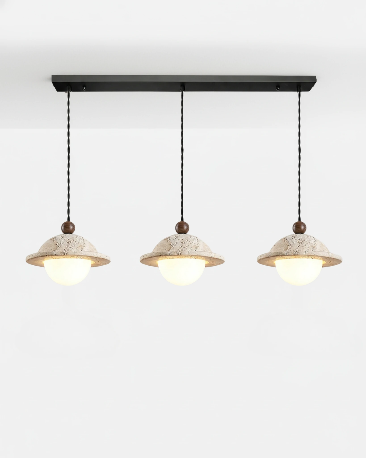 Three travertine pendant lights SOVA No.01 Linear-Three, saucer pendants lit in a row from a black ceiling bar