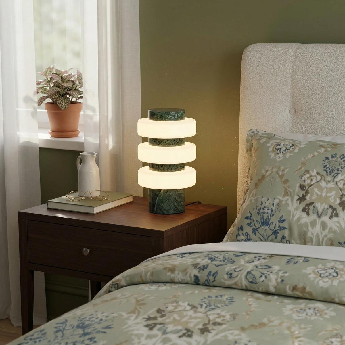 Travertine table lamp PIETRA No.05 in emerald marble lit on a nightstand beside a bed with floral bedding