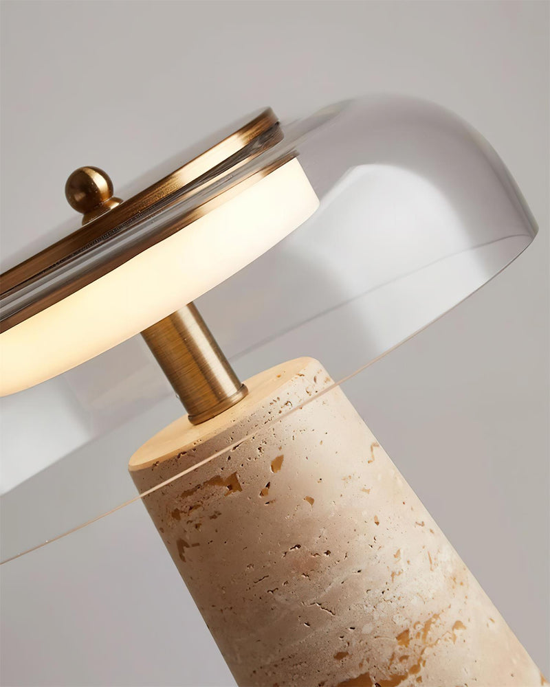 Close-up of the brass collar and lit glass dome of the travertine table lamp MORA No.01 above the stone column