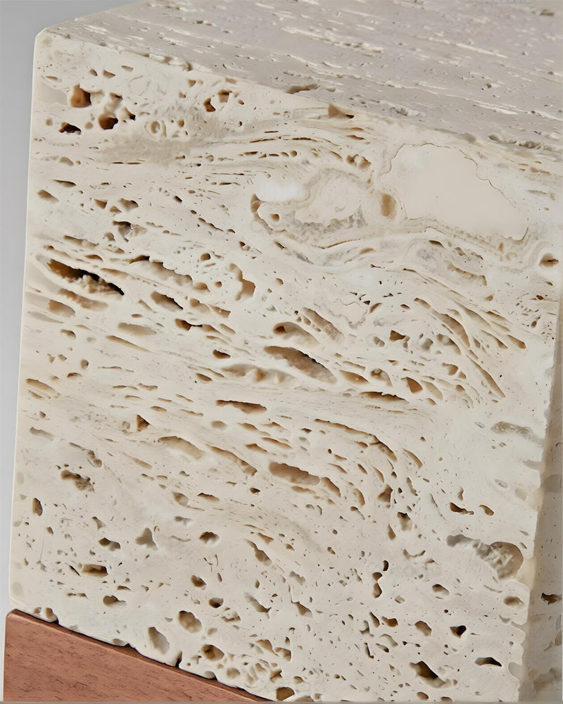 Close-up of the pitted cream travertine surface and walnut base edge of the MORA No.05 travertine table lamp