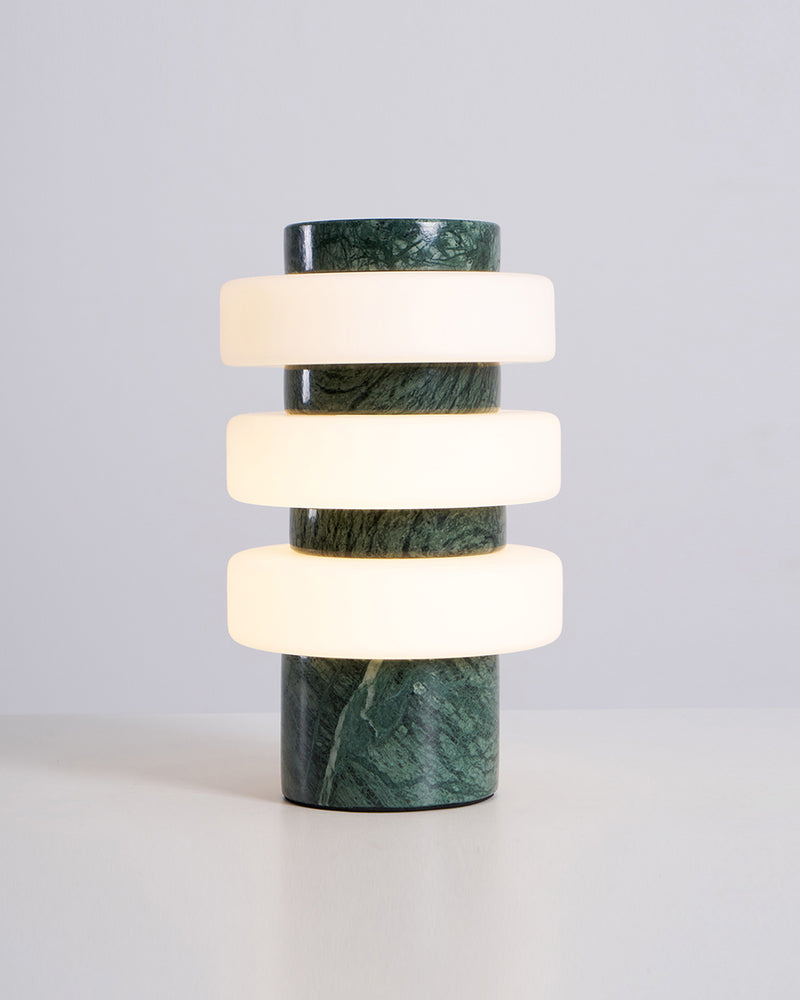 Travertine table lamp PIETRA No.05 in emerald marble with its three acrylic rings glowing warm white