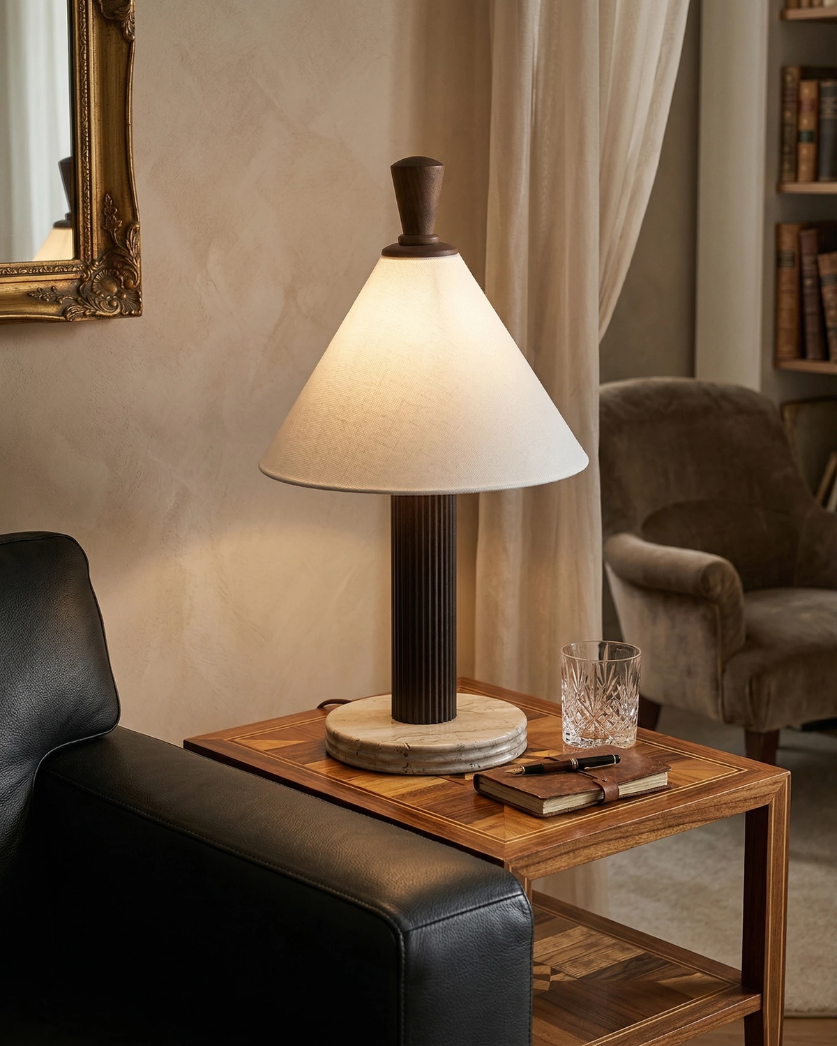 Travertine table lamp IMOLA No.01 in walnut lit on a wood side table beside a black leather chair