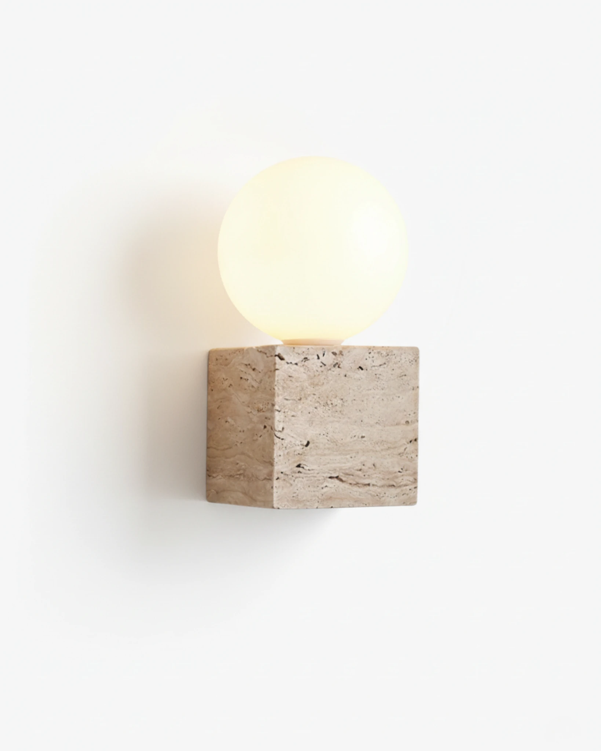 Travertine vanity light MODENA No.01, yellow travertine cube topped by an opal glass globe, switched on