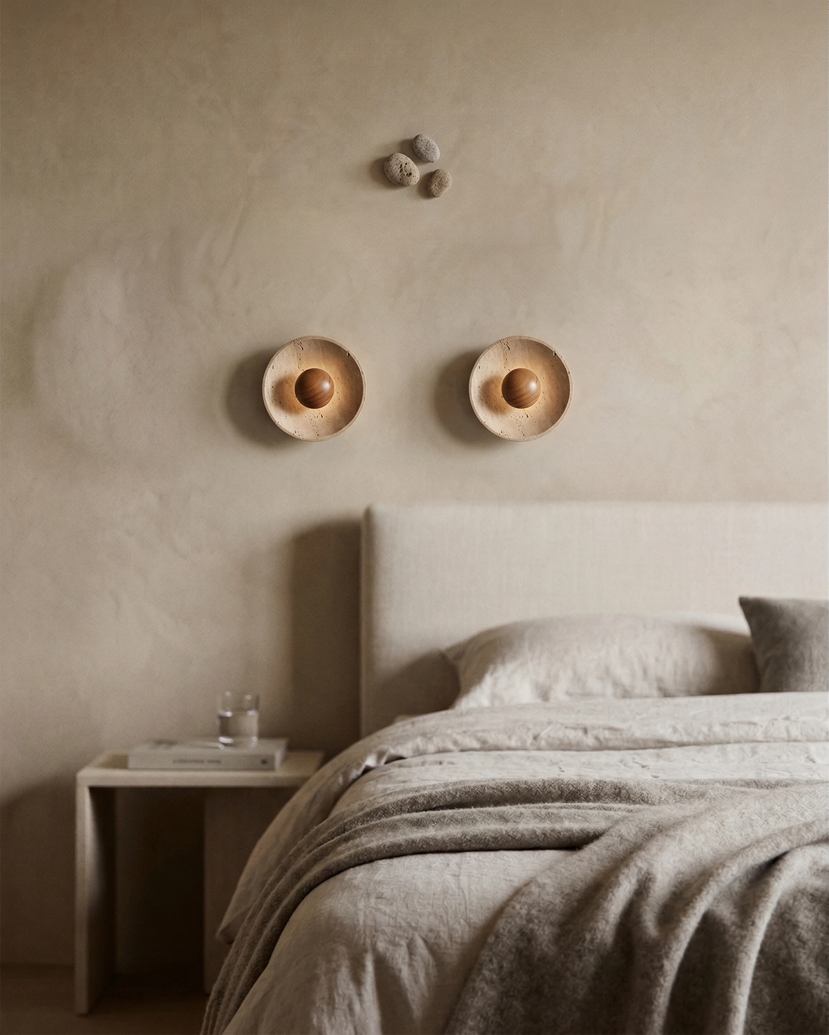 Pair of travertine wall sconces PRATO No.01 mounted above a bed with a white headboard and linen bedding