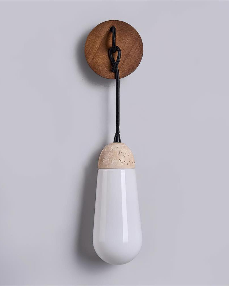 Travertine wall sconce CORTO No.02 close view, unlit opal drop hanging from a knotted cord under a walnut disc