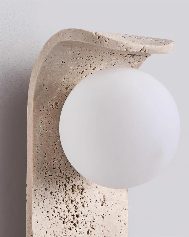Close-up of the curved travertine top and opal globe of the travertine wall sconce ARCO No.01, unlit