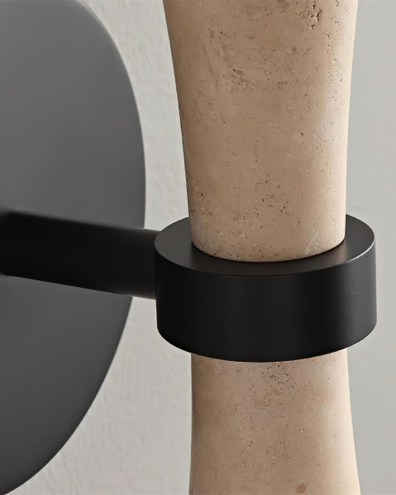 Close-up of the black metal bracket gripping the cream travertine body of the travertine wall sconce VETTA No.01