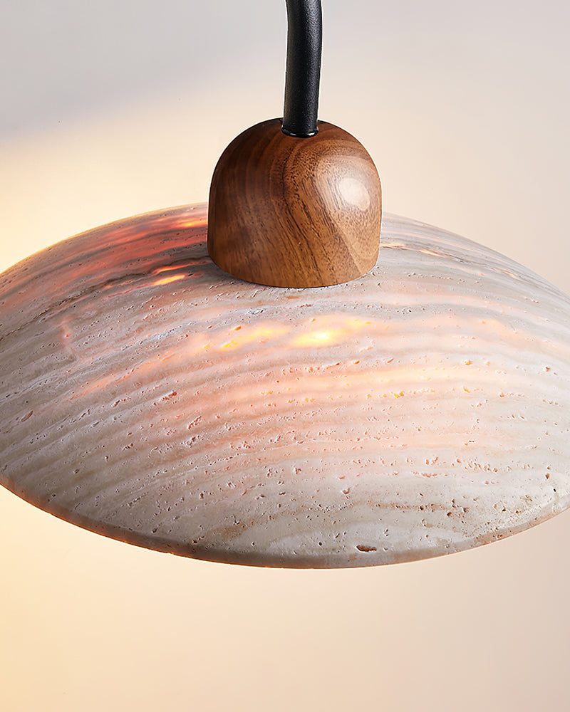 Close-up from below of the lit opal globe and travertine disc of the IVERA No.01 travertine wall sconce with walnut cap