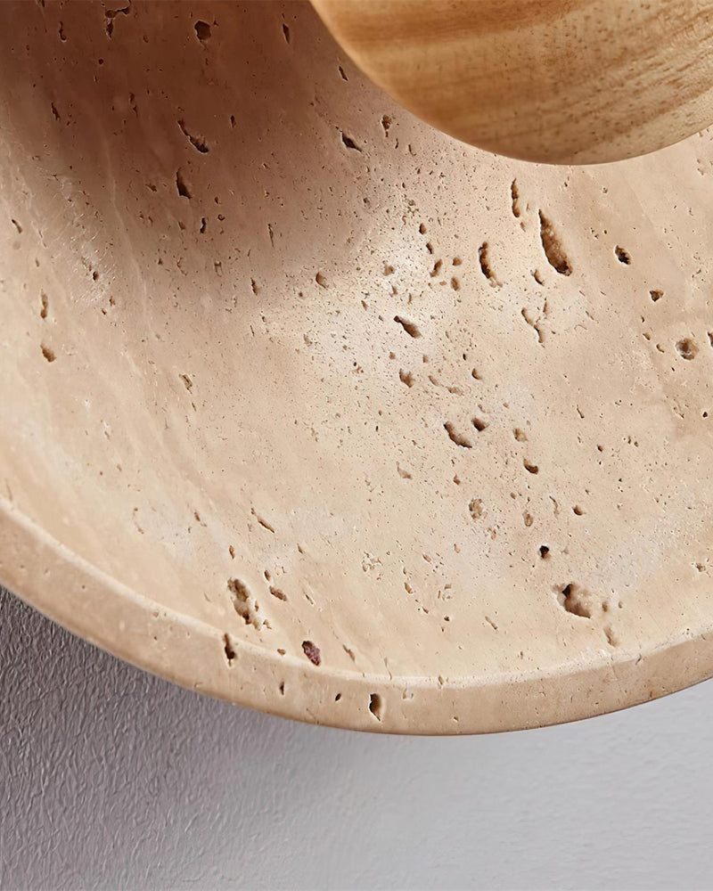 Close-up of the pitted travertine saucer and walnut center of the travertine wall sconce PRATO No.01