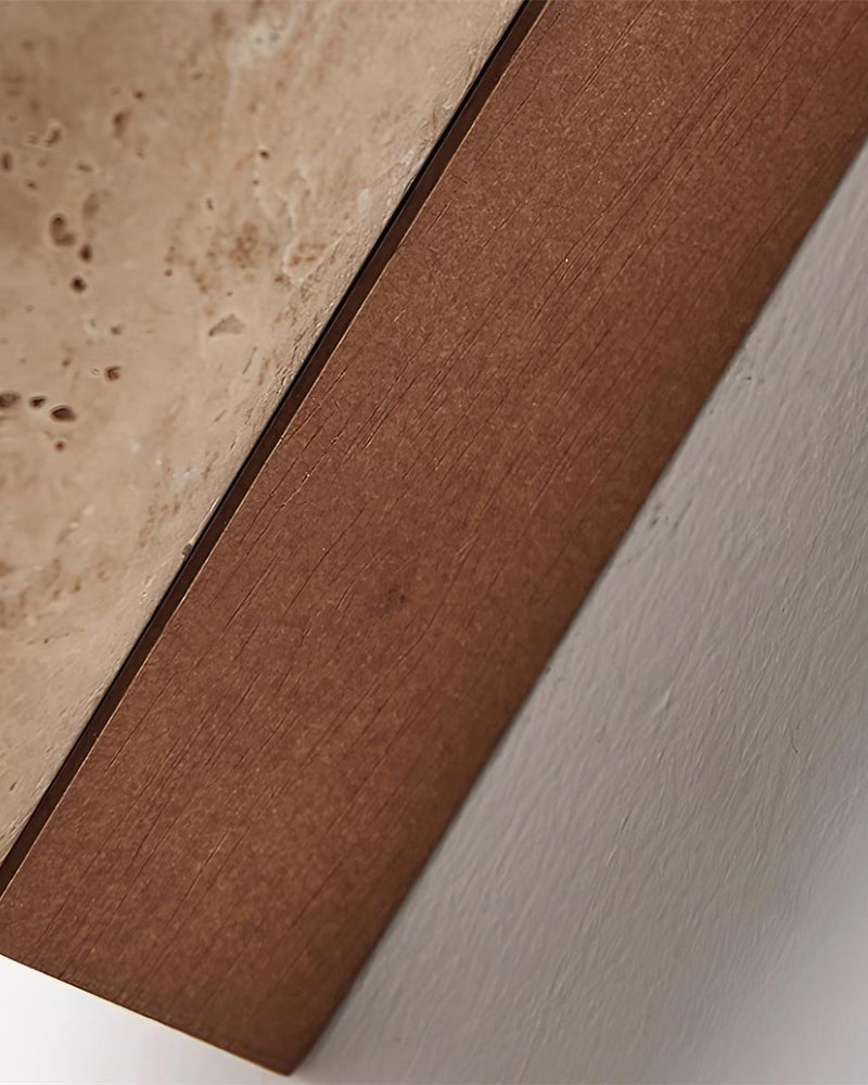 Close-up of the walnut bracket meeting the pitted travertine on the travertine wall sconce STELO No.02