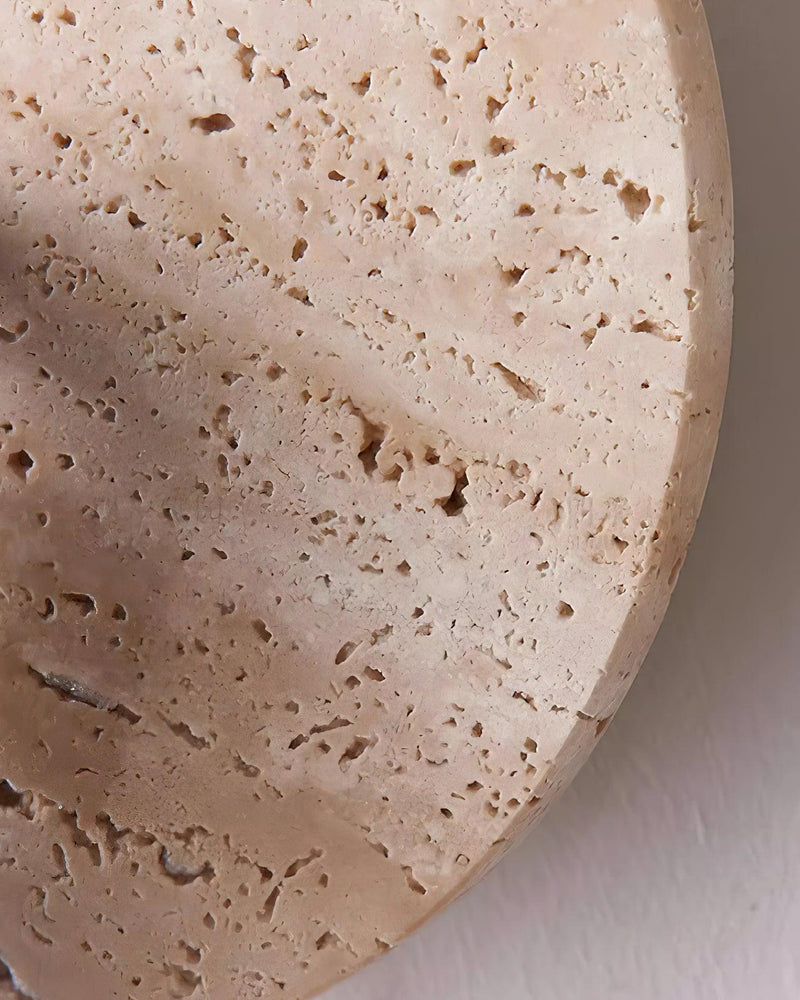 Close-up of the pitted yellow travertine disc of the VITRU No.03 wall sconce showing the natural stone texture