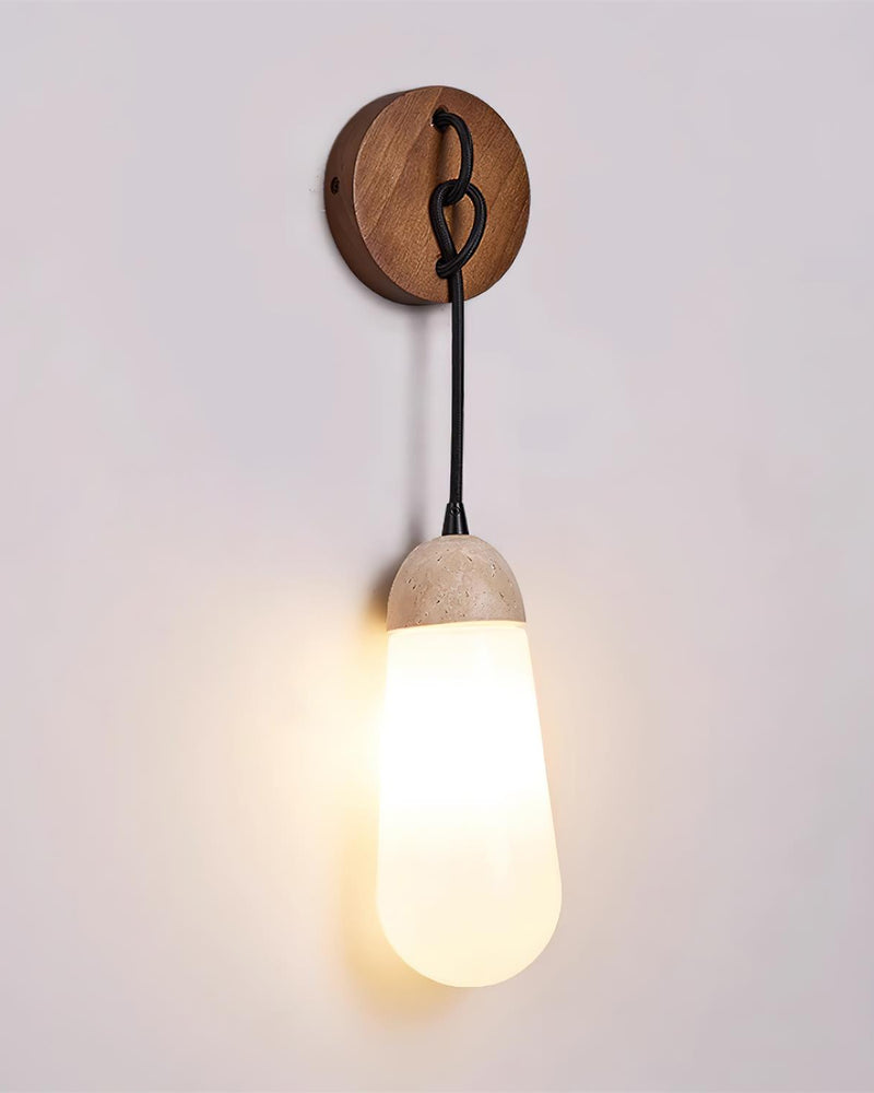 Travertine wall sconce CORTO No.02 switched on, opal teardrop glowing beneath its travertine cap