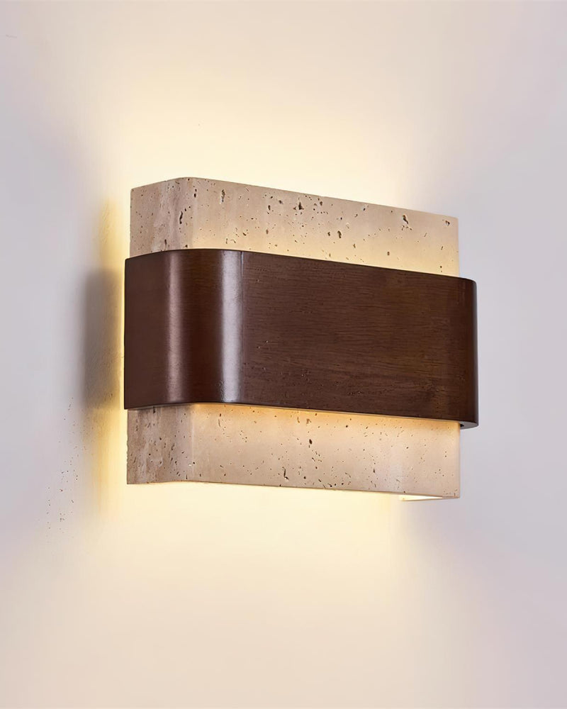 Travertine wall sconce MASSO No.01, cream stone block wrapped in walnut, switched on with glow above and below on the wall
