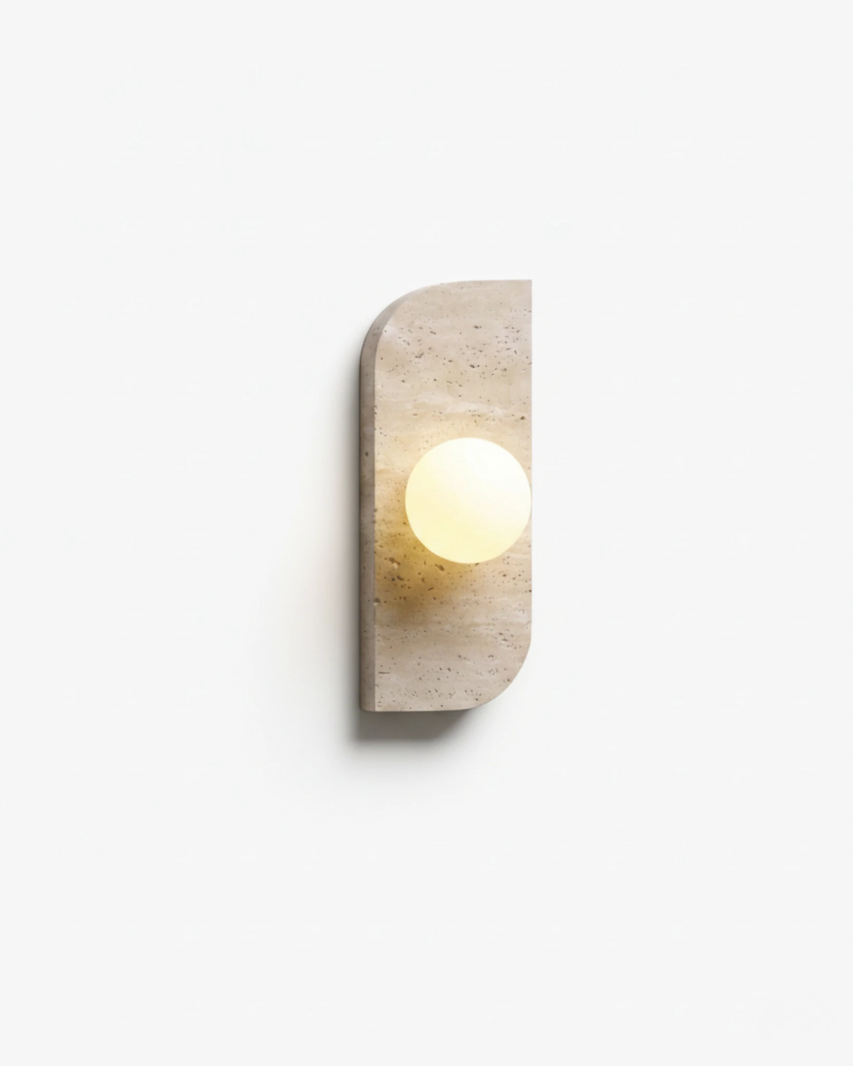 Travertine wall sconce GENOVA No.01, asymmetric travertine plate with a glowing opal globe on a white background