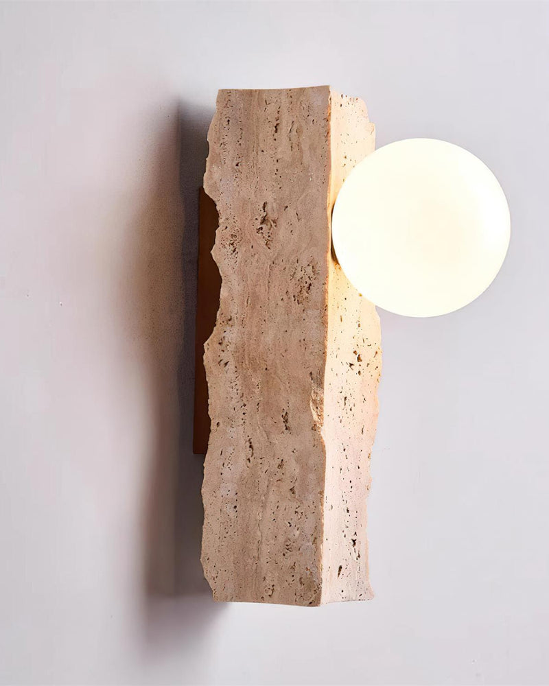 Travertine wall sconce KANSO No.03 angled view, glowing opal globe set against a raw-edged travertine slab