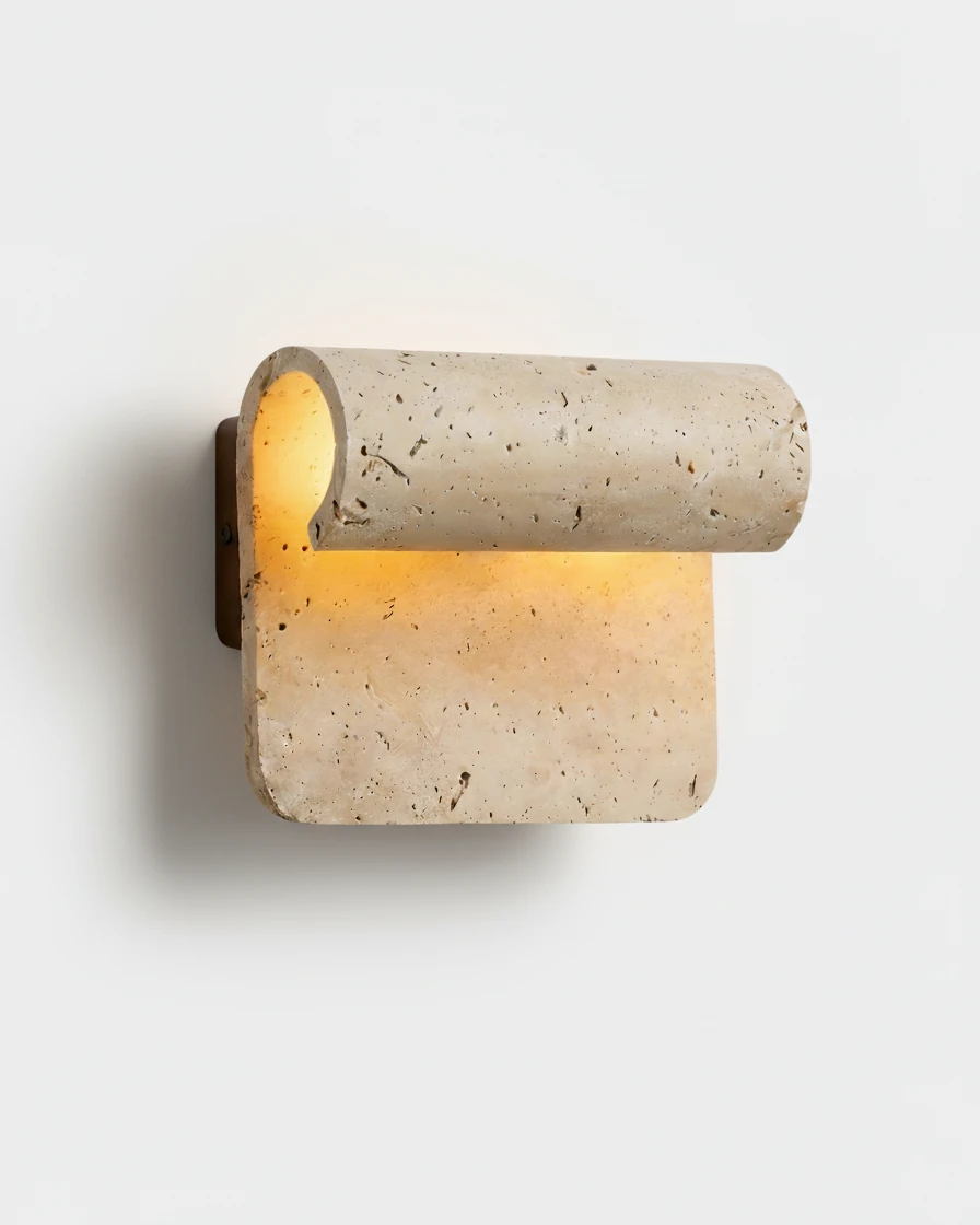 Travertine wall sconce RIVA No.01 switched on, warm light spilling from under the sculptural travertine curl