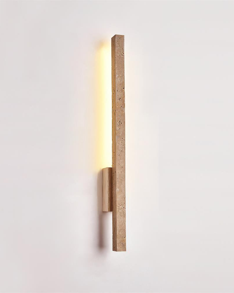Travertine wall sconce VITRU No.02 seen from an angle, lit travertine bar held off the wall by a wood bracket