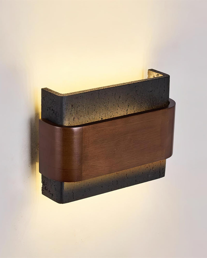 Travertine wall sconce MASSO No.01 in Volcano Black, angled view of the dark stone block with walnut belt lit up and down