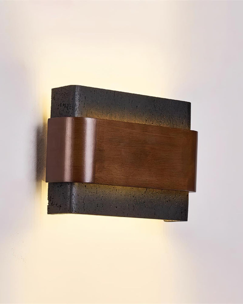 Travertine wall sconce MASSO No.01 Volcano Black seen straight on, black travertine and walnut band with light spilling out