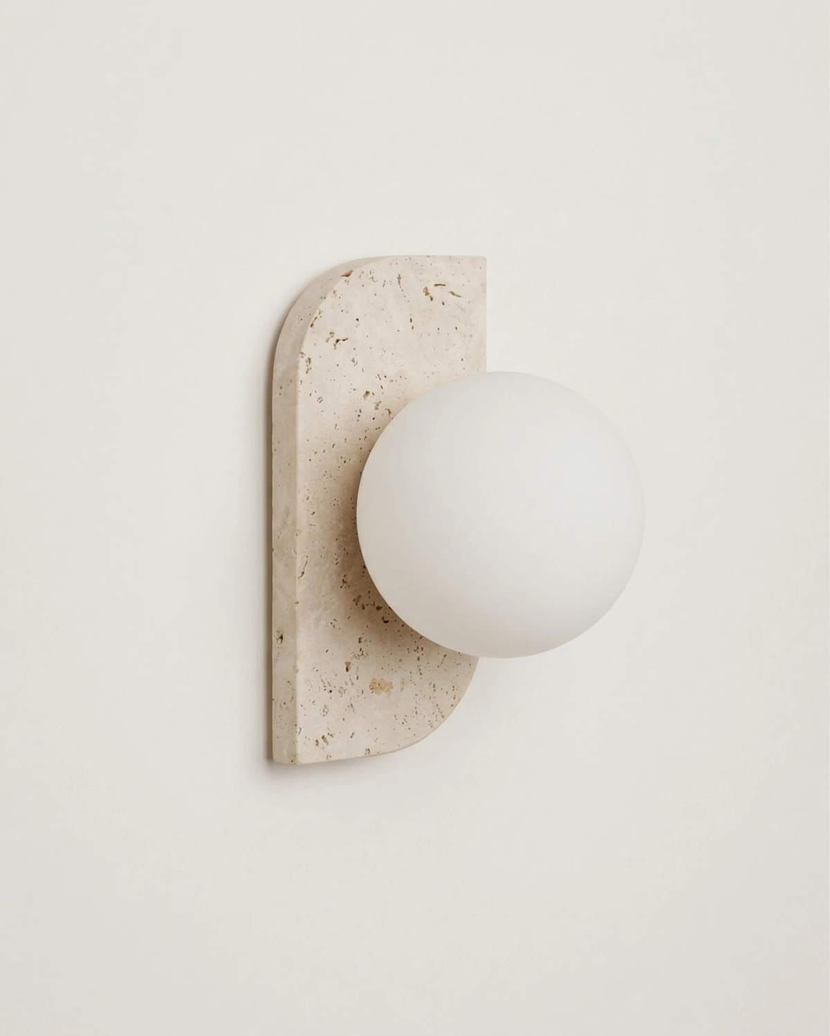 Travertine wall sconce PRATO No.03 single globe, unlit opal globe on a half-moon travertine plate, angled view