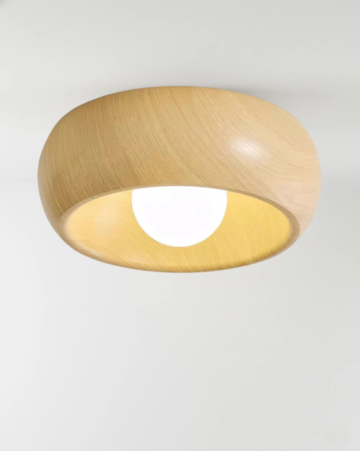 Wood flush mount ceiling light OMBRA No.01 in Light Oak, pale wood dome glowing with the opal bulb lit