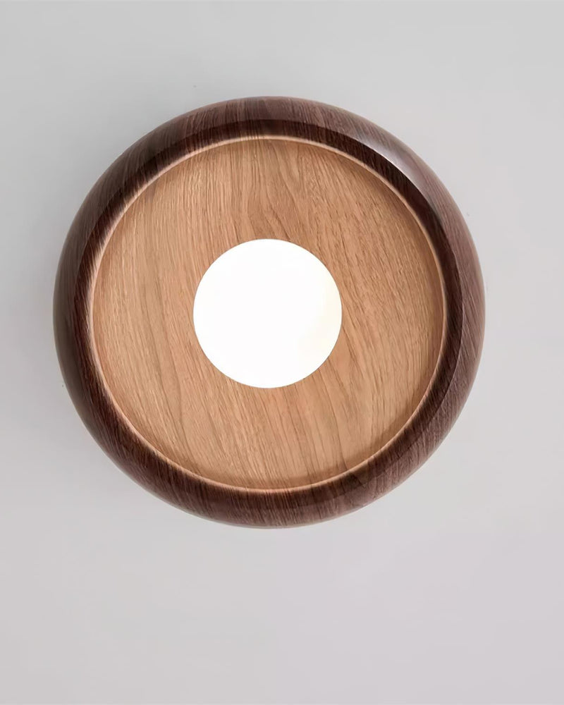 Wood flush mount ceiling light OMBRA No.01 seen straight from below, dark rim, lighter wood inner face and center opal bulb