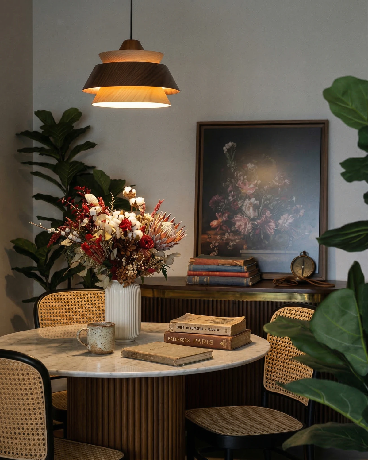 Wood pendant light BOSCO No.01 in dark walnut lit over a round marble table with cane chairs and flowers