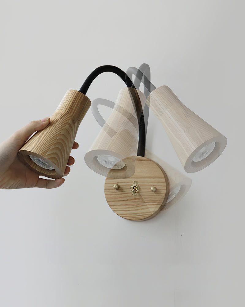 Wood wall sconce RIGA No.07 in light ash with a hand tilting the cone head to show the pivoting gooseneck
