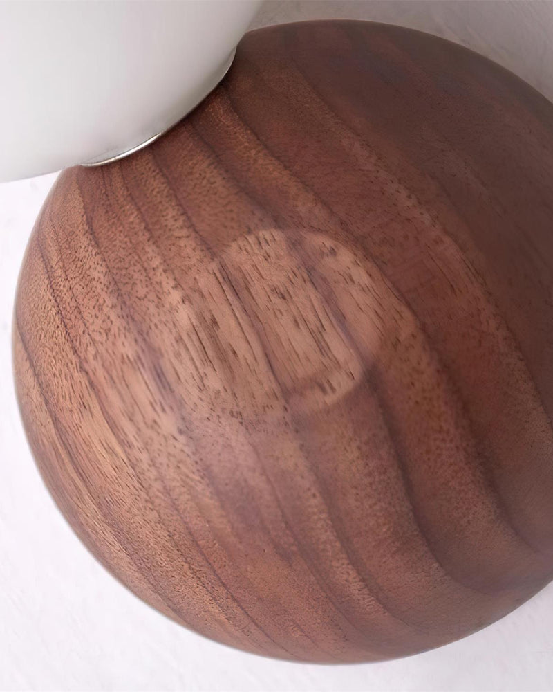 Close-up of the solid walnut pebble of the ALBE No.01 wood wall sconce showing the grain beneath the opal globe