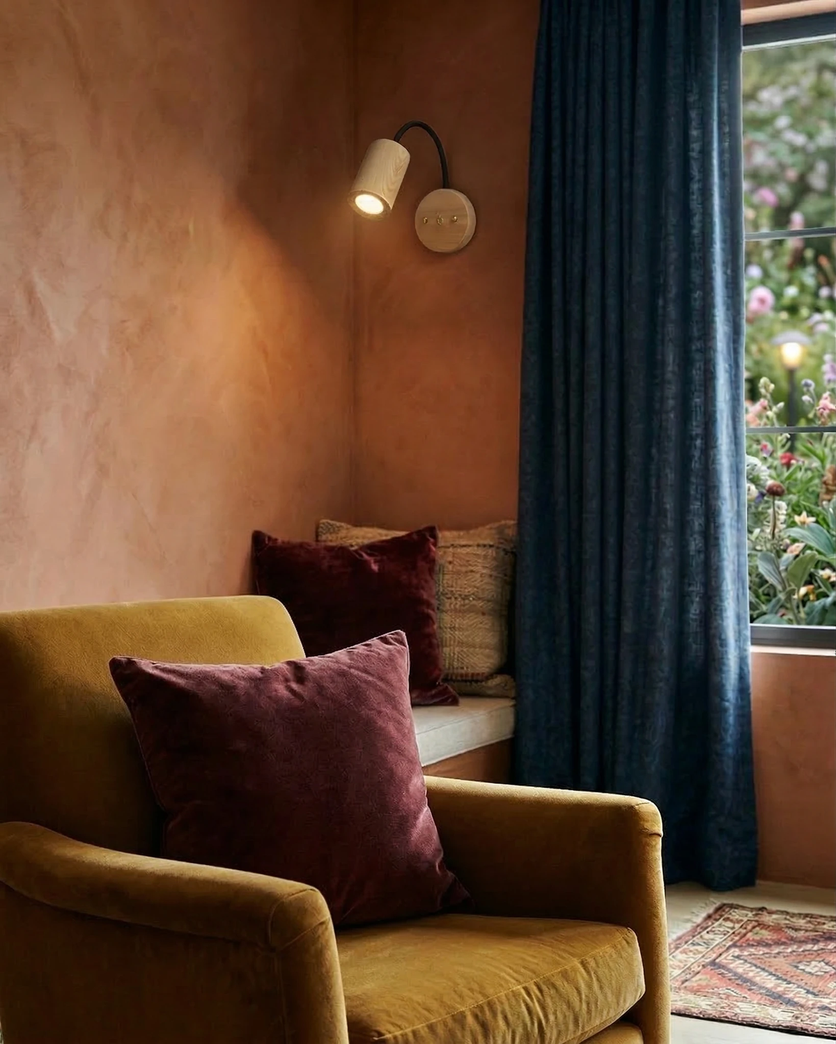 Wood wall sconce RIGA No.07 switched on above a mustard velvet armchair by a window with blue curtains